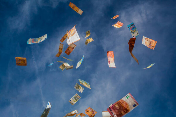 Falling money from the blue sky with clouds