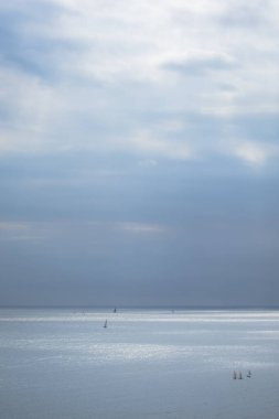 Sakin mavi deniz, yelkenli ve bulutlu gökyüzü