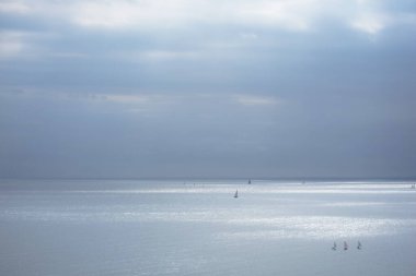 Sakin mavi deniz, yelkenli ve bulutlu gökyüzü