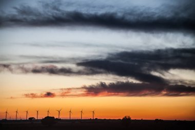 Rüzgar jeneratörleri alanında mavi ve turuncu gökyüzü ile gün batımı manzarası