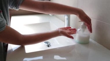 Koronavirüs salgınını önlemek için ellerini sabunla yıkayan küçük bir kız.