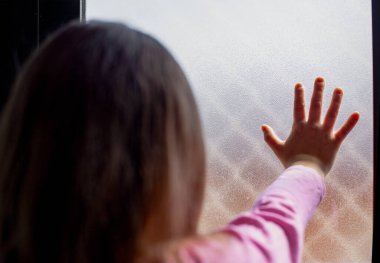 Kilitleme kavramı: eli penceresinde olan küçük bir kız hapsedilmeyi ve karantinayı özlüyor