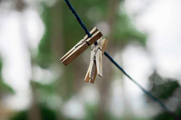 Wooden clothespins fastened on a blue rope with the background out of focus