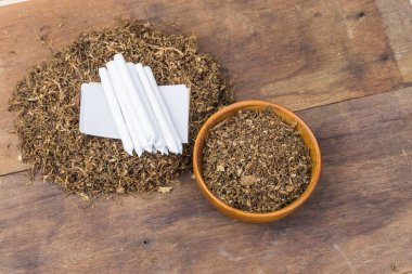 Sigara ve tütün, ahşap kasede tütün ve sigara içmek için yuvarlanan tütün, siyah ahşap arka planda. Üst görünüm.