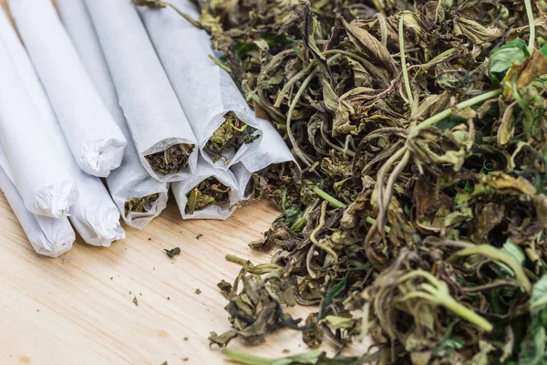 Yüksek kalitede marihuana tomurcuğu ve ahşap masanın üzerinde ot otu olan sarma yeri kapatın. Seçici Odaklanma.