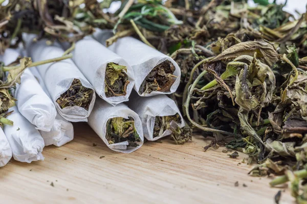 Yüksek kalitede güçlü kenevir tomurcuğu ve ahşap masada esrar ile sarılmış bir yerde yakın plan. Seçici Odaklanma.