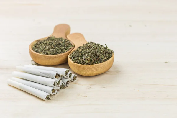 Esrarlı esrar. Kaşık dolusu ot, öğütücü ve ahşap arka plan. Esrar sarmak ve ot içmek..