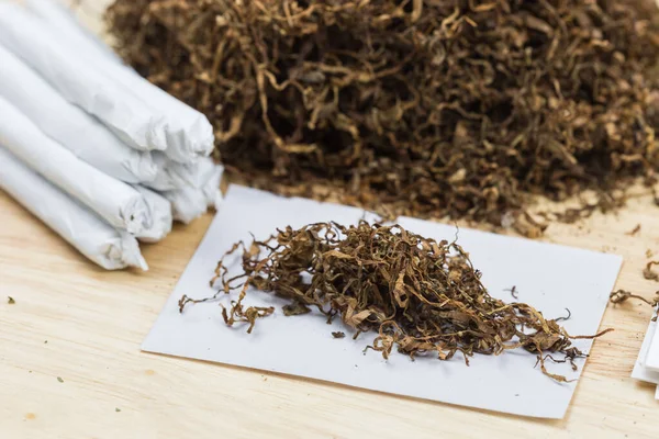 Tütün eklemleri ahşap arka planda ve beyaz kağıtta sarmaya hazır..