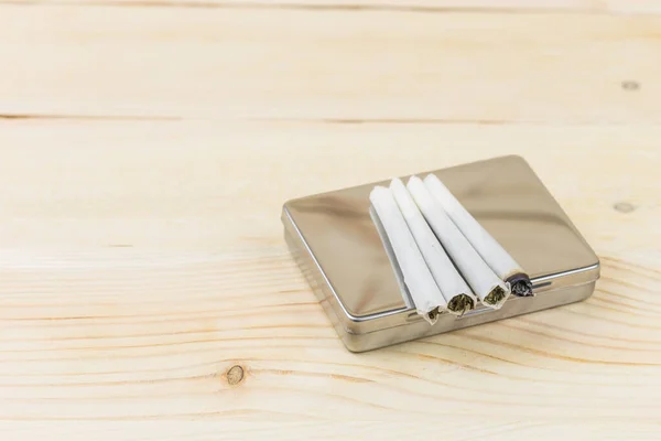 Ahşap arka planda esrar tüttürmek için sigara kutusu..