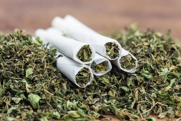 Yüksek kalitede güçlü kenevir tomurcuğu ve ahşap masada esrar ile sarılmış bir yerde yakın plan. Seçici Odaklanma.