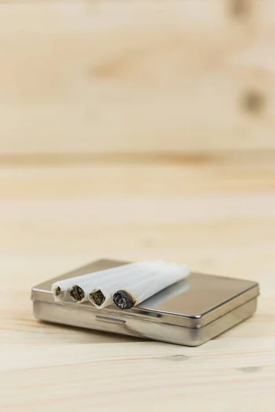 Ahşap arka planda esrar tüttürmek için sigara kutusu..