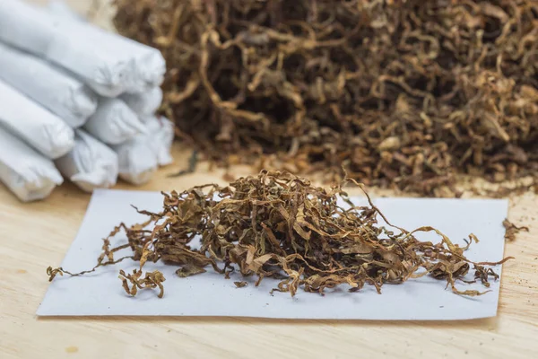 Tütün eklemleri ahşap arka planda ve beyaz kağıtta sarmaya hazır..