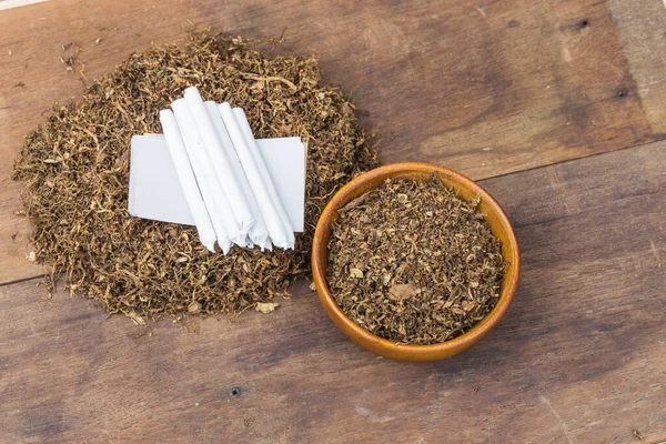 Sigara ve tütün, ahşap kasede tütün ve sigara içmek için yuvarlanan tütün, siyah ahşap arka planda. Üst görünüm.