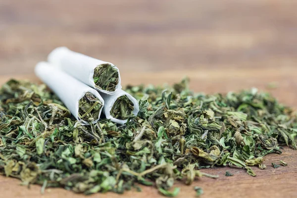 Marihuana, ot ya da esrarı siyah bir masaya yakın çekim ve sarılmış esrar.