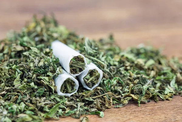 Yüksek kalitede güçlü kenevir tomurcuğu ve ahşap masada esrar ile sarılmış bir yerde yakın plan. Seçici Odaklanma.