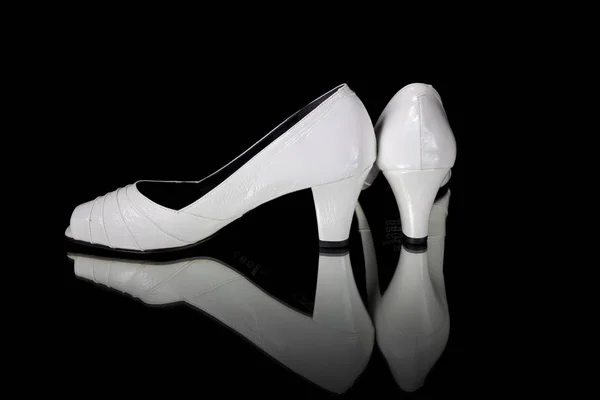 Женская белая кожаная обувь на черном фоне — стоковое фото