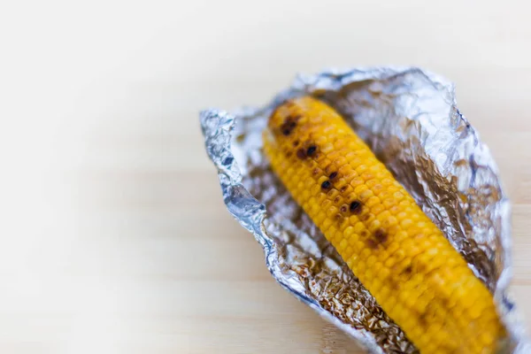 Maíz amarillo al horno en papel de aluminio sobre fondo blanco — Foto de Stock