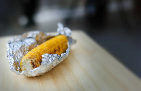 Maíz amarillo al horno en papel de aluminio sobre fondo blanco — Foto de Stock