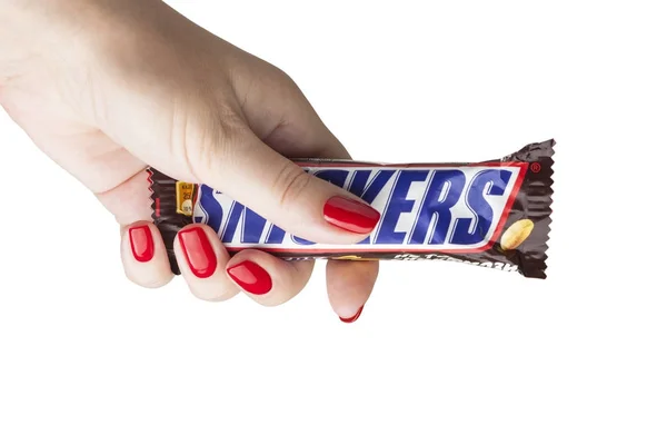 Mão segurando uma barra de chocolate Snickers — Fotografia de Stock