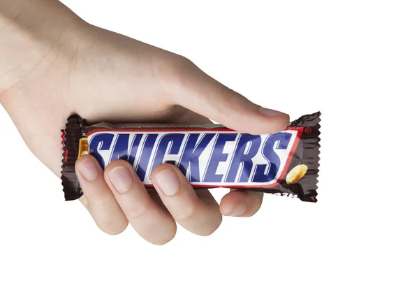 Mano sosteniendo una barra de chocolate Snickers — Foto de Stock
