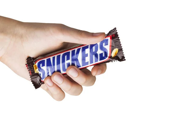 Mano sosteniendo una barra de chocolate Snickers — Foto de Stock