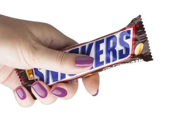 Mão segurando uma barra de chocolate Snickers — Fotografia de Stock