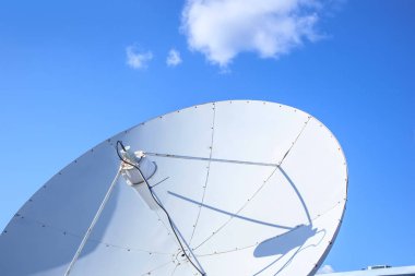 Mavi gökyüzünün arka planında telekomünikasyon için beyaz parabolik uydu anteni.