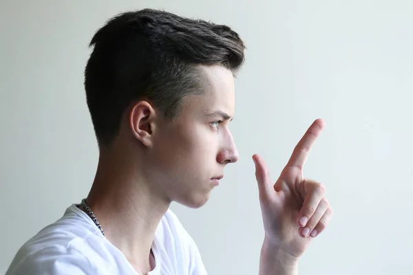 Ung man i profil visar upp finger — Stockfoto