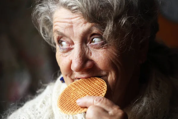 Пожилая женщина ест вафли Лицензионные Стоковые Изображения