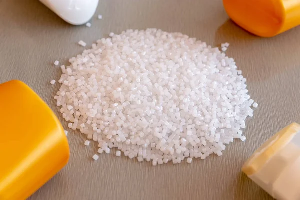 Close-up of plastic polymer granules and plastic bottle. Polymer