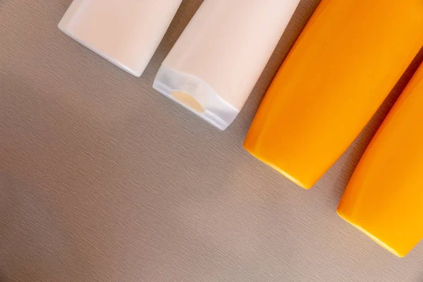 Orange and white shampoo bottles on wooden table background. reu