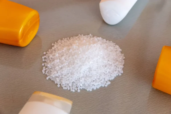 Close-up de grânulos de polímero plástico e garrafa de plástico. Polímero — Fotografia de Stock