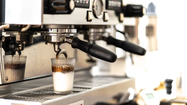 Otomatik kahveden dökülen beyaz sütlü espresso yakın plan.