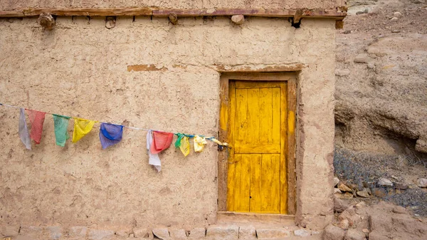 Çamurdan yapılmış evin sarı bir giriş kapısı var. Ve orada 