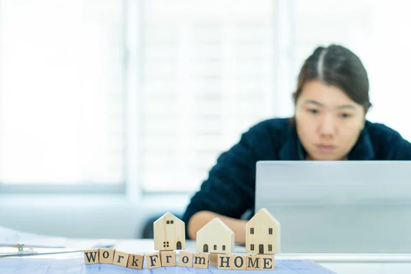 Tahta bloğa odaklan. Bulanık arkaplan Asyalı kadın, evinde çalıştığı süre zarfında telekonferans teknolojisiyle bir dizüstü bilgisayarın önünde oturuyordu. İç işlerinde çalışan iş kadınlarının sorunlarından dolayı. 