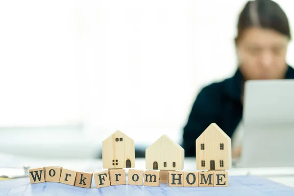 Tahta bloğa odaklan. Bulanık arkaplan Asyalı kadın, evinde çalıştığı süre zarfında telekonferans teknolojisiyle bir dizüstü bilgisayarın önünde oturuyordu. İç işlerinde çalışan iş kadınlarının sorunlarından dolayı. 