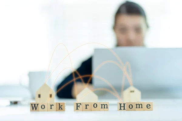 Ev konsept.Bulanık arka planda çalışan Asyalı bir kadın ev bilgisayarının önünde oturmuş ahşap bloktaki işine odaklanmış evde çalışan ya da işten sonra bilgisayarla uğraşan ya da sıkılmış bir iş kadını..