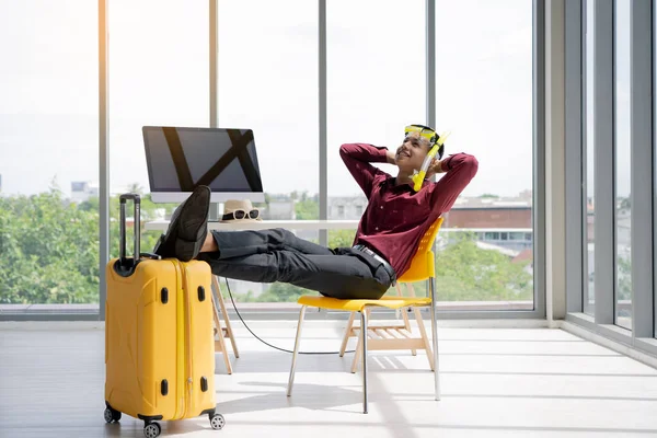 Şirket çalışanları yıllık tatillerde seyahat etmeyi ve dinlenmeyi düşünüyor. Genç Asyalı işadamı ofiste tatile hazırlanıyor..