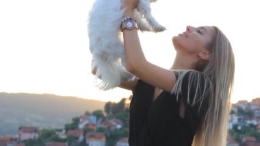 Attractive Happy Blonde Female Holding and Hugging Maltese Dog Puppy