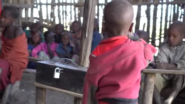 Дети племени Масаи сидят в классной хижине в грязной одежде. Африка — стоковое видео