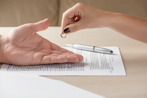 Жена и муж подписывают документы о разводе, женщина возвращает обручальное кольцо — стоковое фото