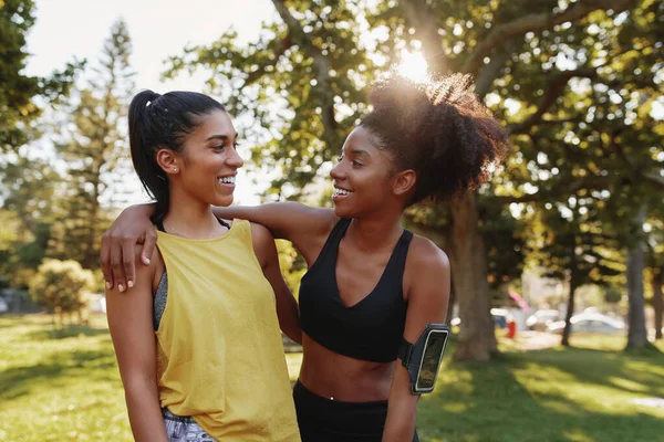 Ritratto di una sorridente amica multietnica che si abbraccia in un parco nella giornata estiva - allegre amiche che sorridono insieme in un parco — Foto Stock