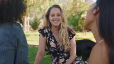 Gülümseyen genç sarışın bir kadının parkta arkadaşlarıyla vakit geçirmesini yakından görmek. Gülümsemek, sohbet etmek ve gülmek.