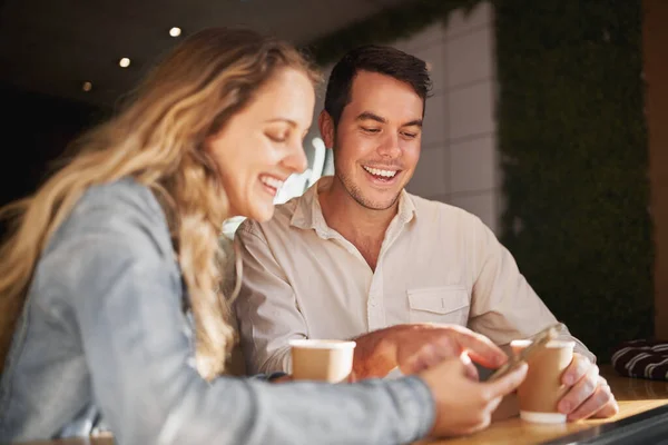 Gelukkige jonge vrienden zitten samen in de coffeeshop met behulp van smartphone - glimlachen moderne echte mensen — Stockfoto