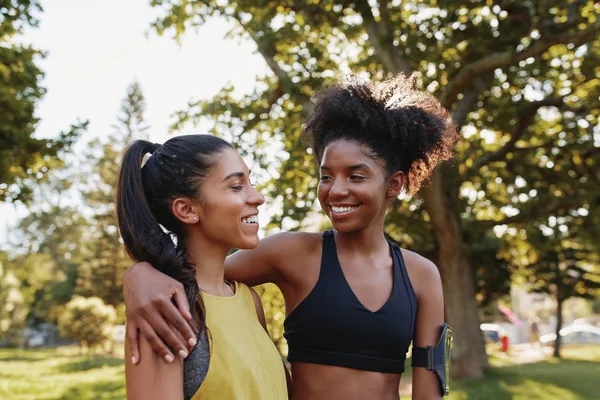 Vrolijke jonge sportieve multi-etnische vrouwelijke vrienden knuffelen elkaar en glimlachen in het park - gelukkige positieve vrienden in het park voor het sporten — Stockfoto
