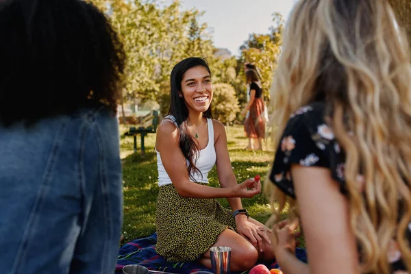 Retrato de una joven amiga feliz sentada en el césped verde pasando el tiempo juntos en el parque - grupo de amigas haciendo un picnic en el parque —  Fotos de Stock