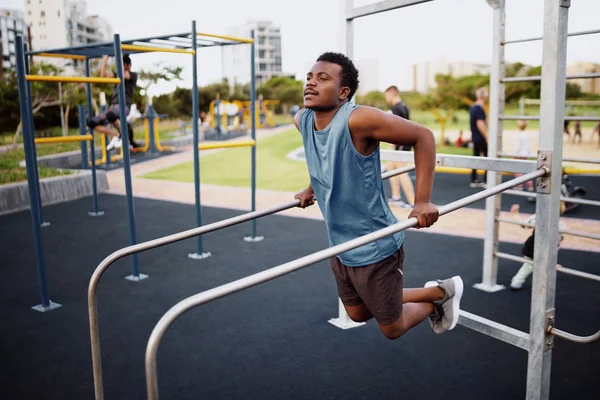 Joven deportista en forma de tríceps y bíceps en barras horizontales en el parque del gimnasio como rutina de entrenamiento crossfit — Foto de Stock