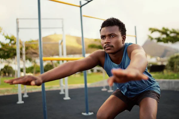 Atletisk ung mand i sportstøj laver fysiske øvelser på udendørs gym park - ung afrikansk amerikansk mand gør squats - Stock-foto