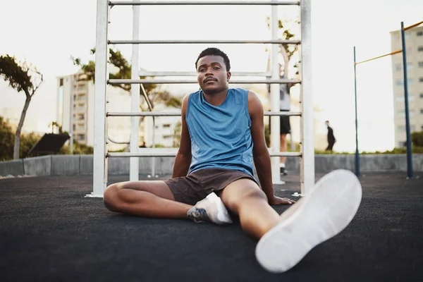 Retrato de un joven afroamericano de fitness cansado sentado en el parque público al aire libre descansando después del entrenamiento —  Fotos de Stock