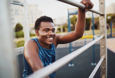 Spor salonunda antrenman yaptıktan sonra dinlenen gülümseyen genç bir fitness oyuncusunun portresi.